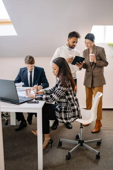 Un bureau contemporain où des mains examinent des données marketing sur un ordinateur portable et des documents papier.
